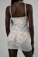 Hand-beaded White mesh mini dress showing sun and spiral detailing and luminous texture.